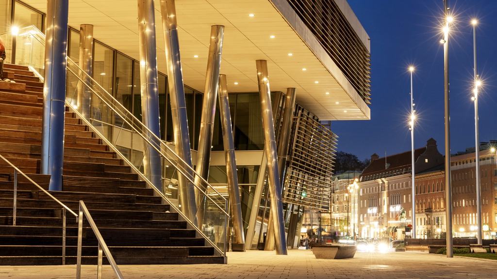 Bilden visar hotellets trappuppgång på kvällen. Hotellet lyser varmt och man ser staden i bakgrunden