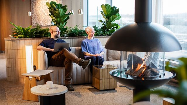 Två personer sitter i en lobby framför en eld
