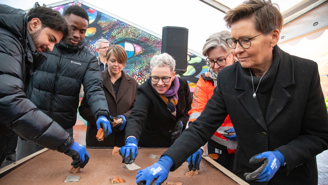 sex personer som lägger ner stenar i en cementplatta