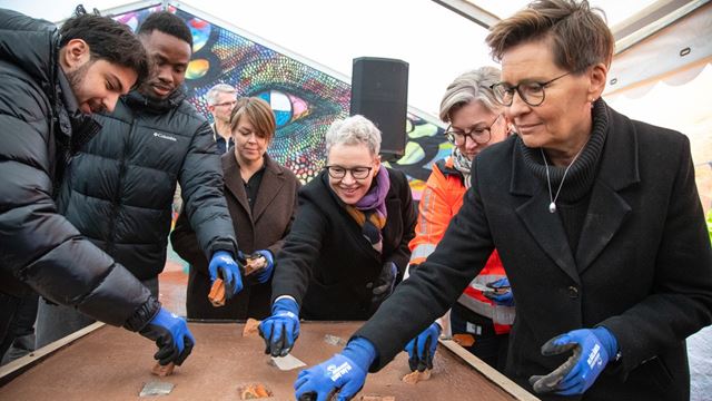 sex personer som lägger ner stenar i en cementplatta
