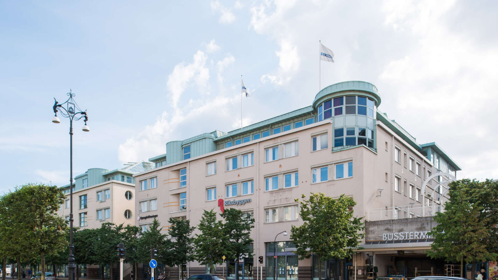Kontorsbyggnad med stora glaspartier, infart till bussterminal vid sidan av byggnaden.